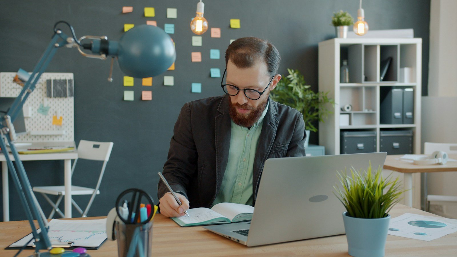 Professional writing notes and drafting content on a laptop at a desk
